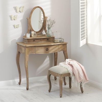 A wooden dressing table with mirror and a small chair in front of it.